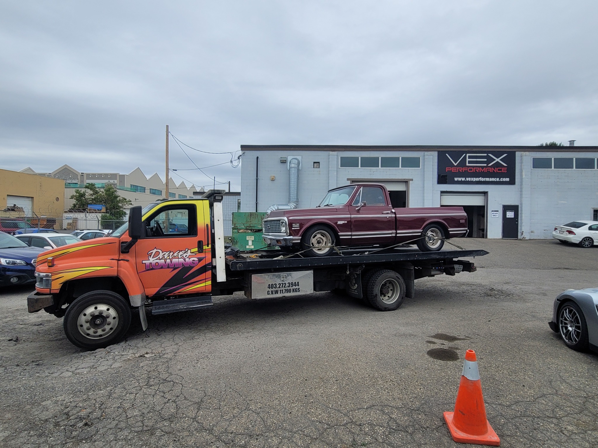 Flatbed towing a vintage pickup at performance shop